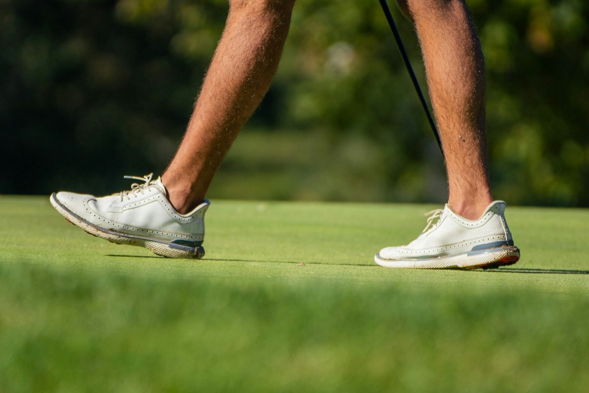Jambes d'un golfeur qui marche sur le green, club à la main